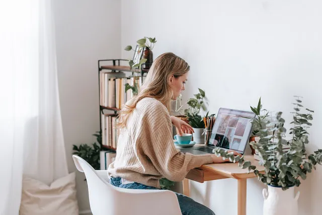 A woman sitting at a desk and researching how to buy a home in Charleston remotely.