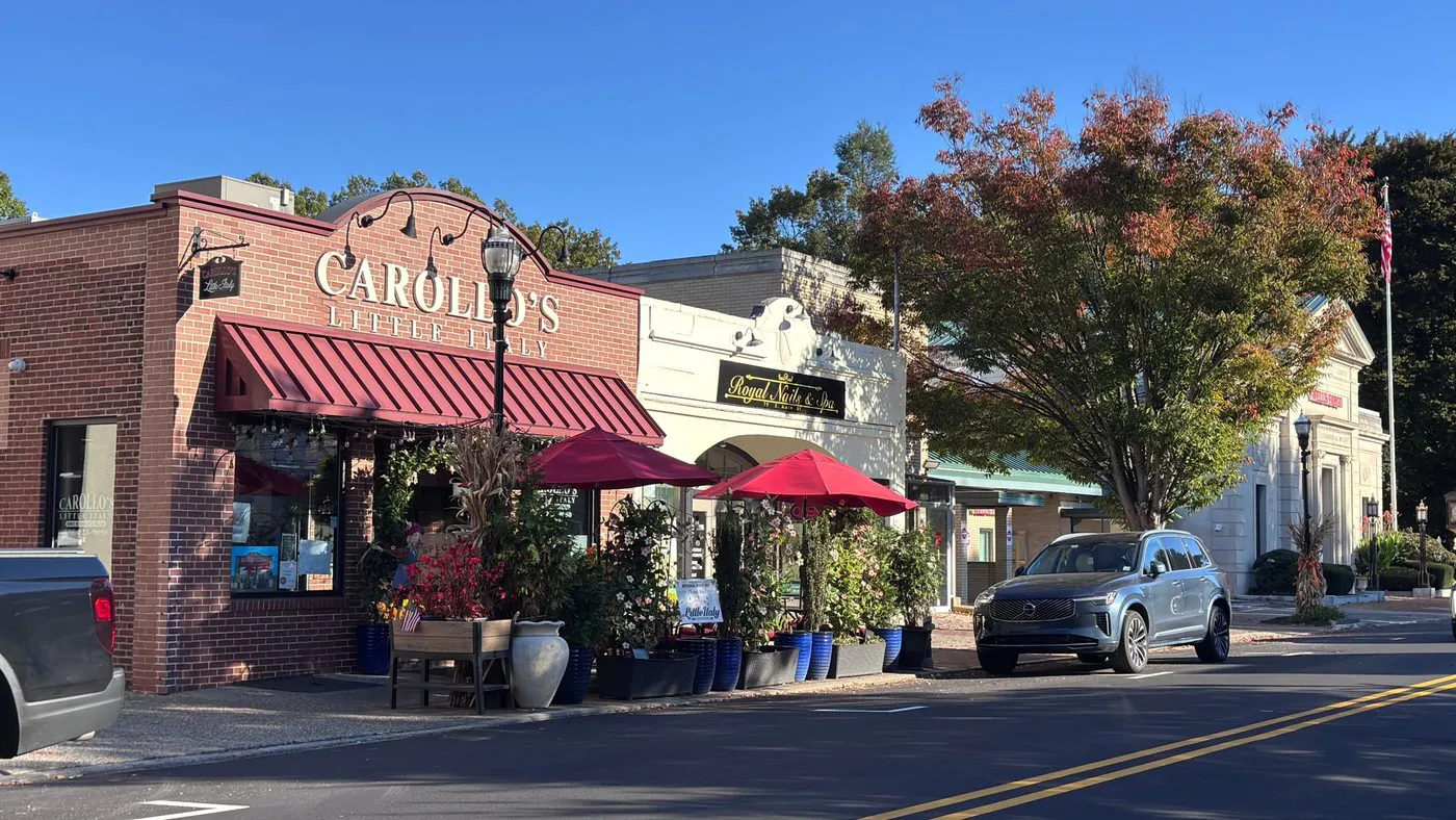 Brick storefront with red awning and outdoor dining on East Main Street in Moorestown, NJ, with fall flowers out front