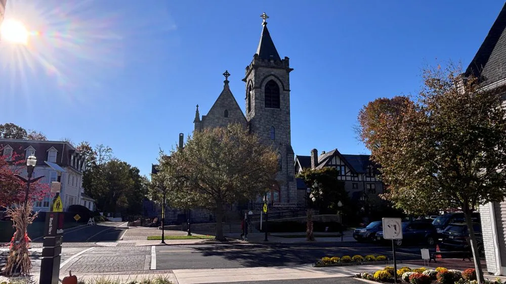 Historic stone church with a tall bell tower near the center of Moorestown, with fall color on the trees