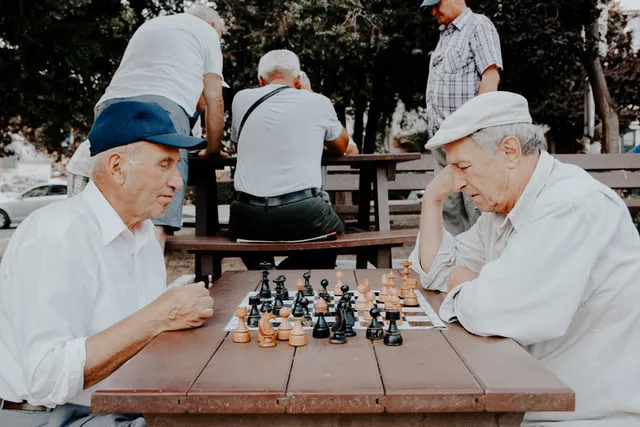 Two men playing chess in a park.