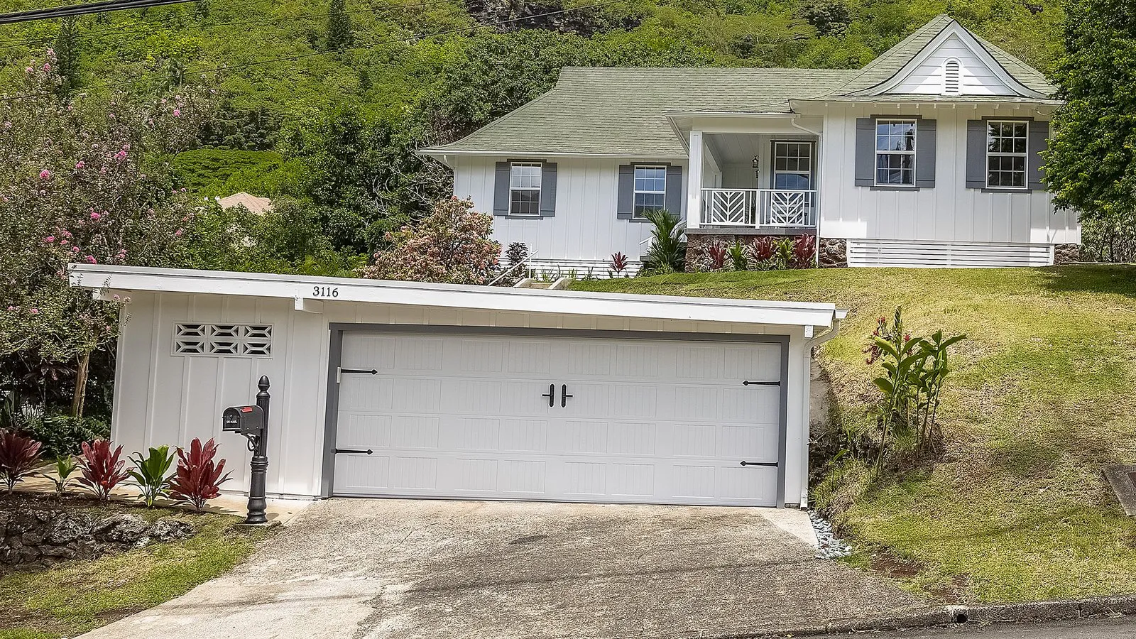Manoa hillside home with a two-car garage and green slopes behind