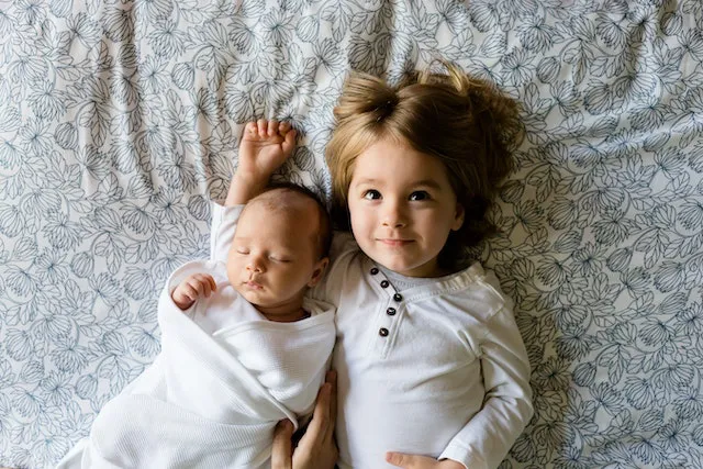 A toddler and a baby lying on a bed. Kids are one of the great reasons to move into a bigger home.