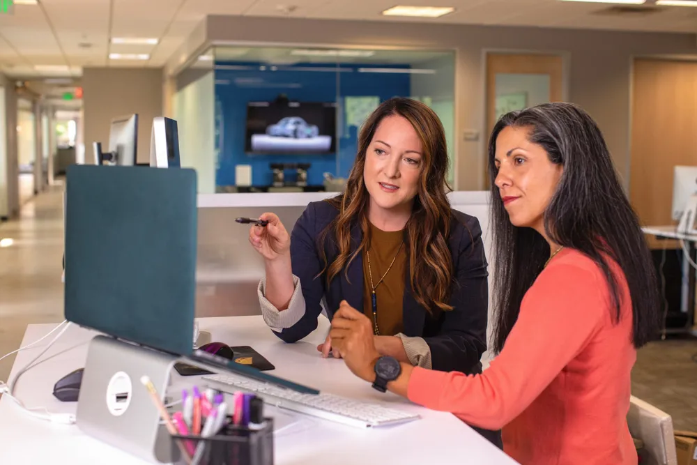 Two women looking at a computer monitor.