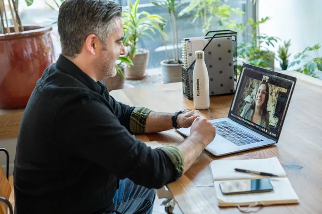 Man in his home office talking to a real estate agent on a video call.