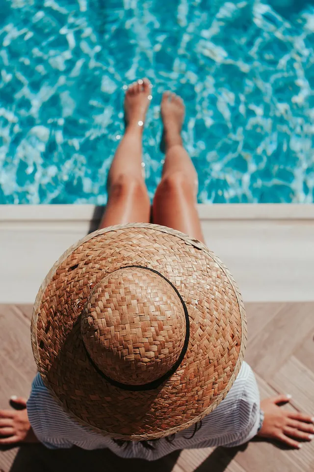 A top view of a woman in a straw hat swimming at a house with a pool for sale in Utah 