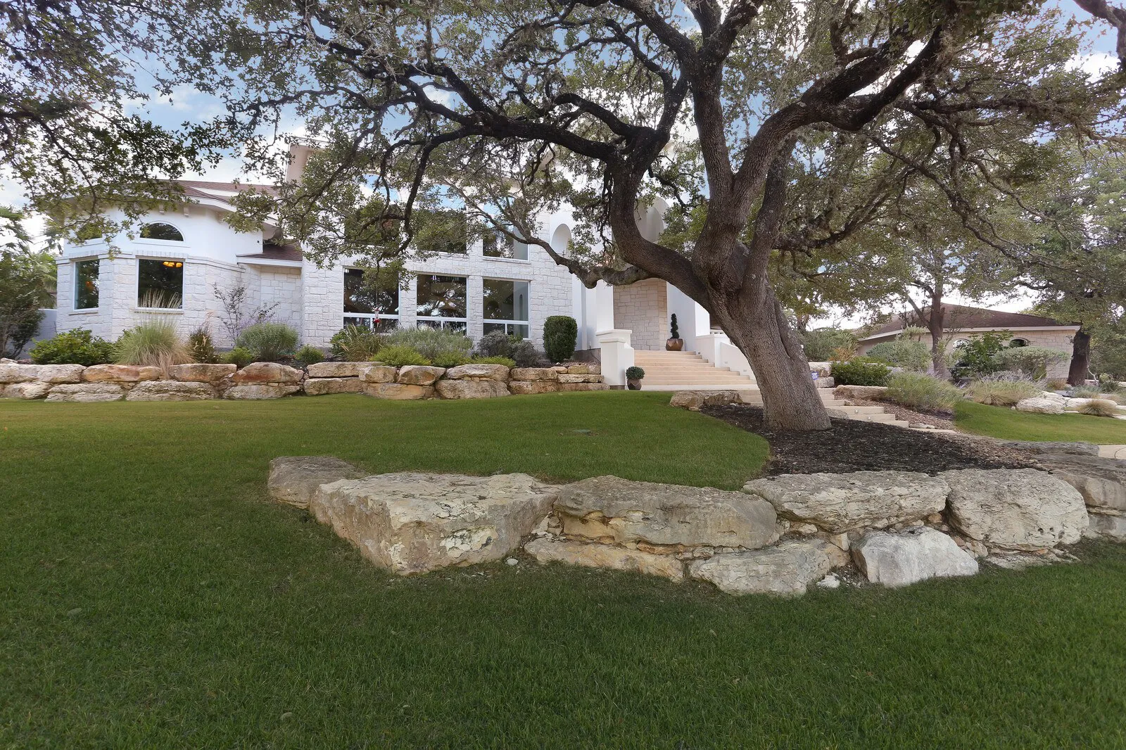 White stone custom home under a large live oak in Cordillera Ranch, Boerne TX